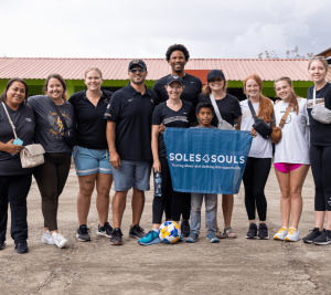 Pictured: a group from the August 2023 Impact Business Immersion in Guatemala. A young boy holds up a banner that says "Soles4Souls."