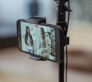 Pictured: A phone is set up on a tripod recording 2 people as part of their company's digital strategies for 2024.