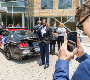 Pictured: Students were able to pose with the racecar that Nashville Superspeedway brought to campus. This image shows a student taking a photo of another student in front of the car that is parked outside of Vanderbilt Business. 