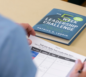 Pictured: Vanderbilt Business' Patrick Leddin's book "The 5 Week Leadership Challenge" is on a desk. A student is sitting at the desk with class materials.
