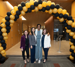 Pictured: Under a gold and black balloon arch, the panelists pose with Kimberly Pace, the panel moderator. From left to right: Feiner, Hutcheson, Lee, Pace.