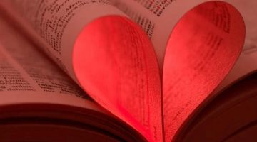 Pictured: An open book has two pages folded up in the shape of the heart. The heart is glowing with a red light. Photo from:proxyminder.