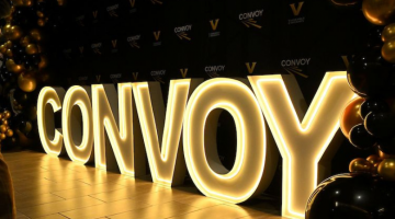 Pictured: LED neon letters spell out "Convoy" under a gold and black balloon arch. The Convoy Conference display was set up in the lobby of Management Hall at Vanderbilt Business.