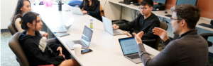 Faculty having a discussion with students at a long table in one of the Political Science instructional spaces
