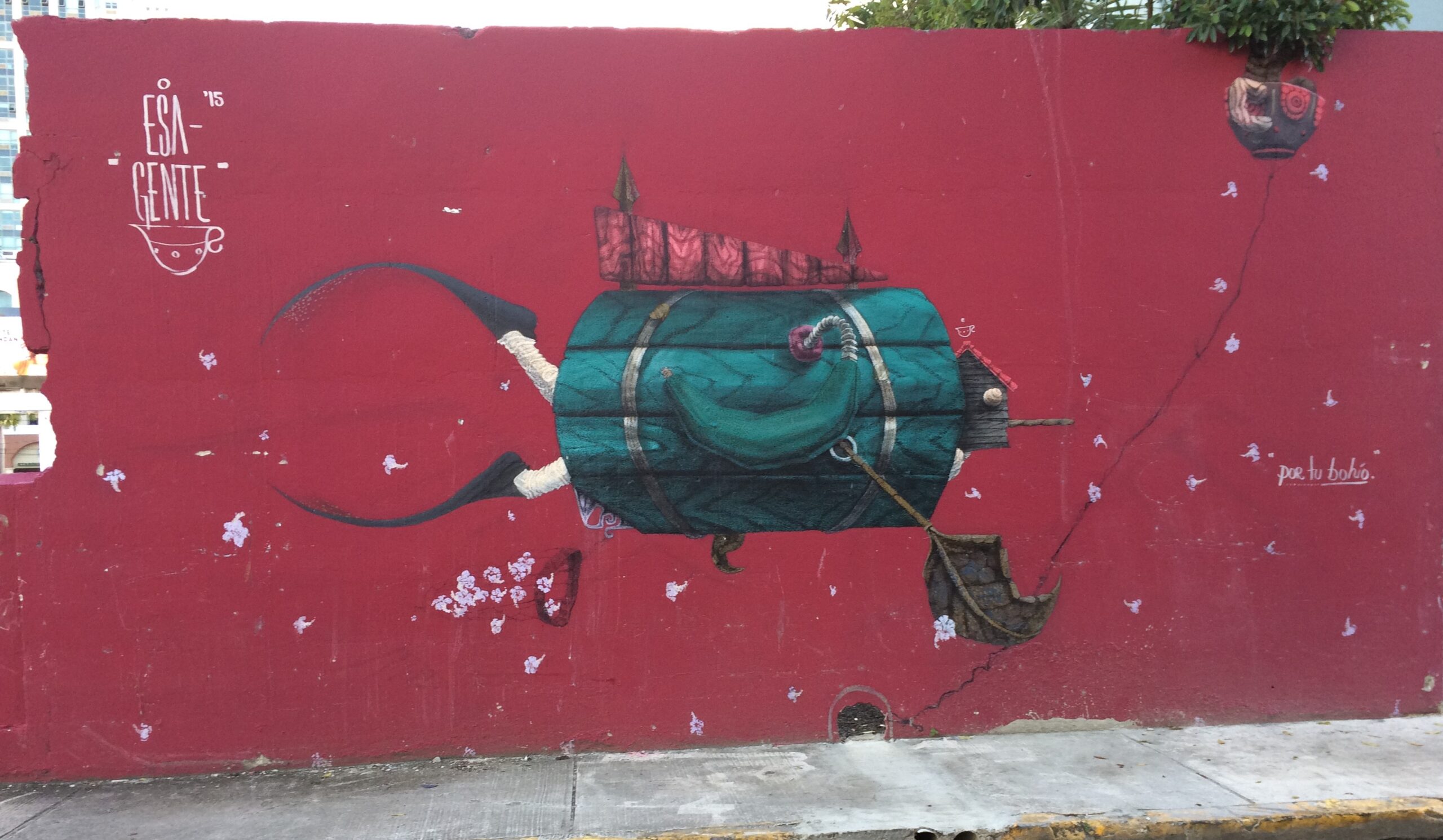 Graffiti on a red wall next to a sidewalk.