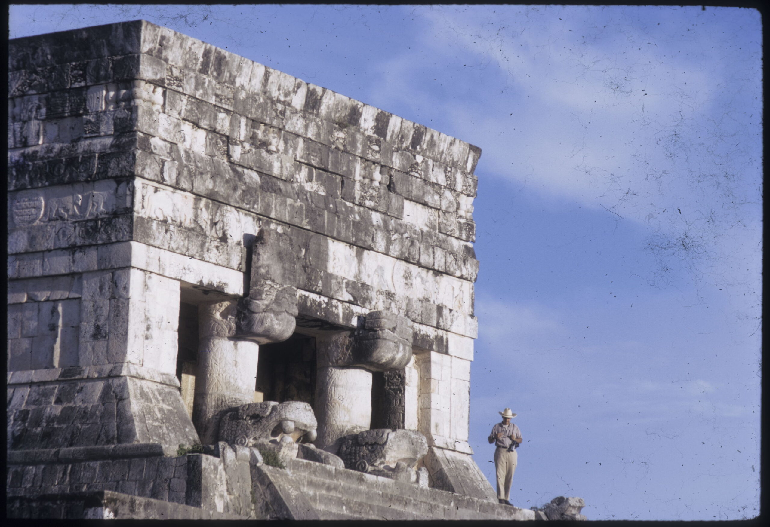Old stone building with man in cowboy hat standing on steps.