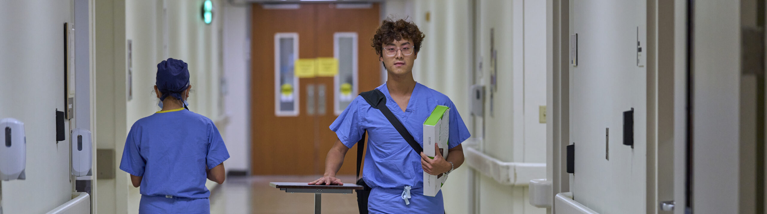 Student in scrubs walking down hall
