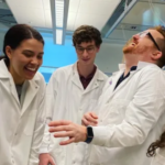 Four people in lab coats laughing
