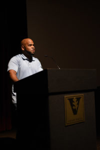 Prof Waters stands at a podium