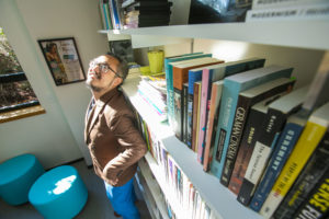 A picture of Iggy Cortez, an Asian man with dark hair and facial hair wearing a brown jacket and blue pants posing and making a silly face