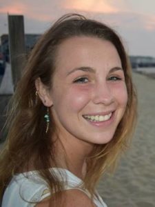 Jess Raff looks over her shoulder at the camera in front of a sunset