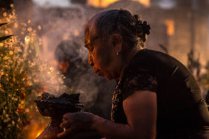 Woman lighting copal incense at the cemetery during the "Alumbrada" vigil in San Andrés Mixquic