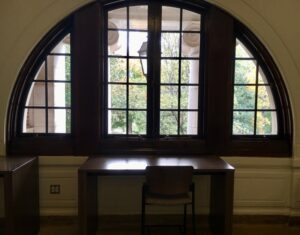 Study desk set under arched windows on the second floor.