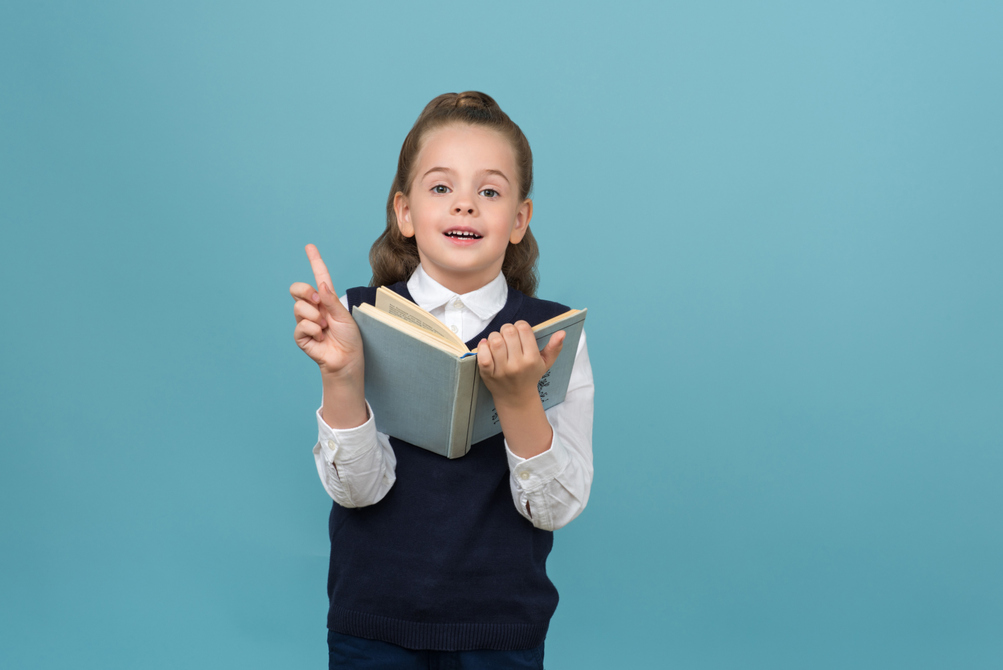 primary-schoolgirl-holding-an-opened-book-and-finger-up