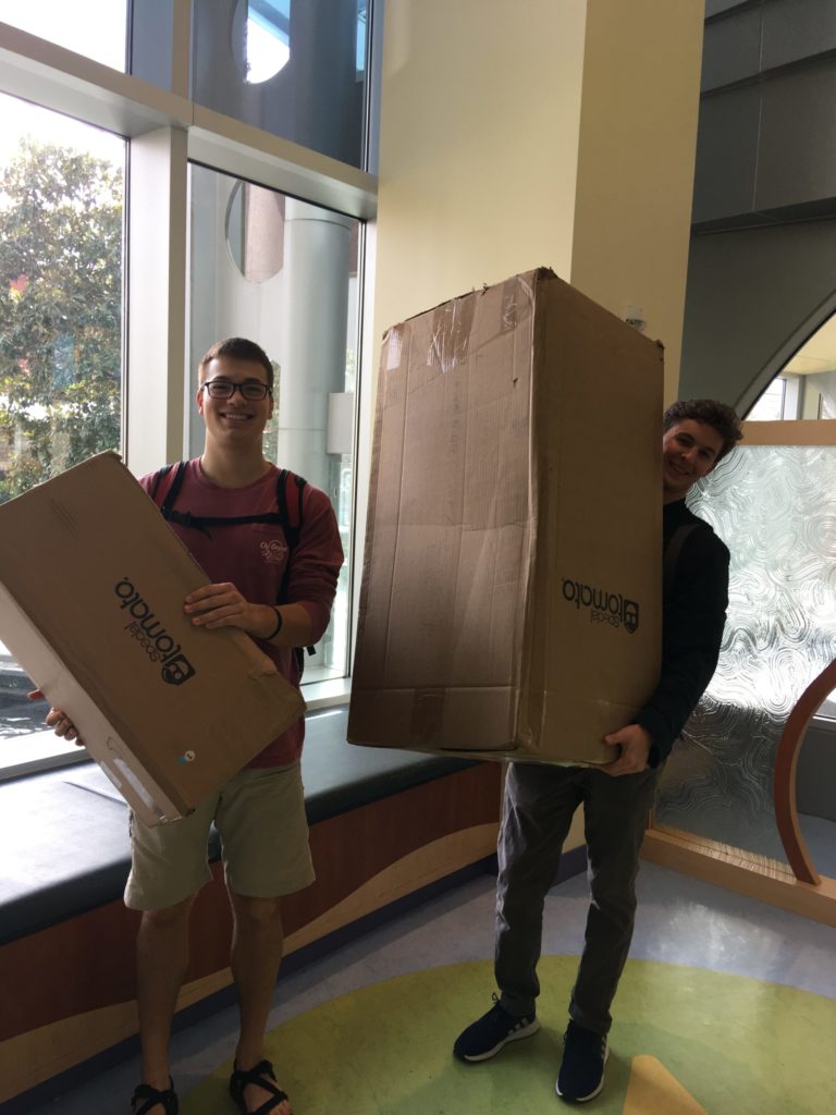 Noah and John carrying chairs into children's hospital