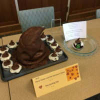 A cake shaped like the Sorting Hat, surrounded by cupcakes with mini-sorting hats on top.
