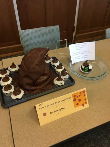 A cake shaped like the Sorting Hat, surrounded by cupcakes with mini-sorting hats on top.