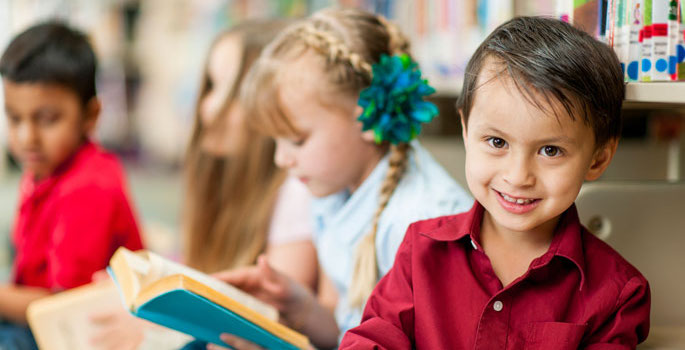 little hispanic boy with book looking at camera