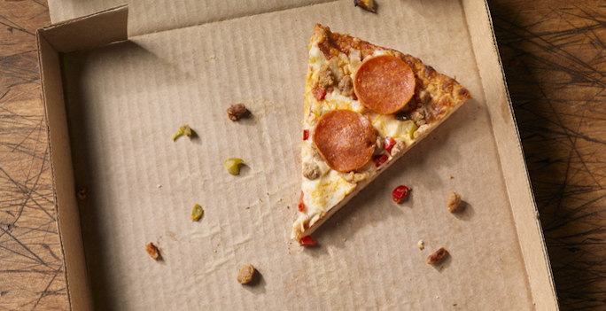 the last slice of supreme pizza in a cardboard takeout box