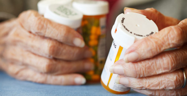 Close up of Senior citizen female holding bottles of prescription medicine.