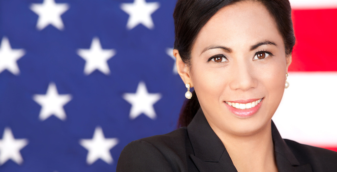 Asian woman in blazer standing in front of American flag