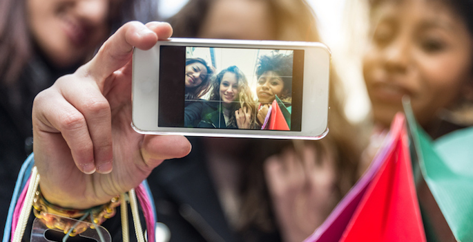 multiracial group of teenage girls taking selfies