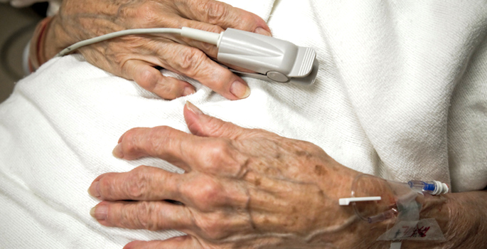 hands of elderly white woman in hospital with oxygen monitor on finger and iv in arm