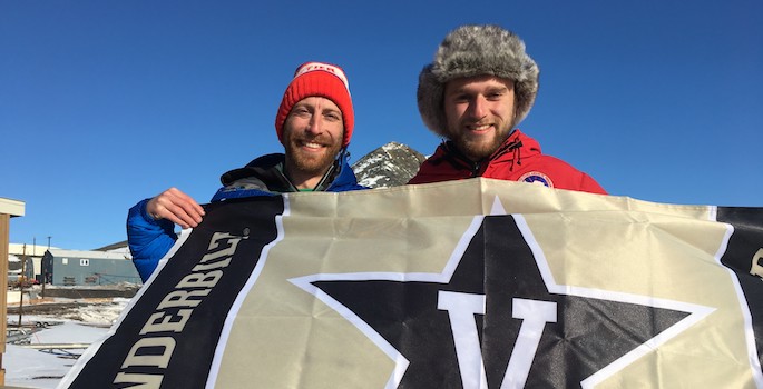 dan and andrew holding a vanderbilt flag in the antarctic snow