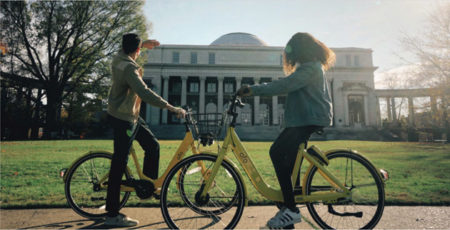 Two students sitting on bikes on campus