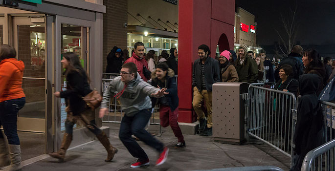 shoppers running from behind barricades into store on black friday