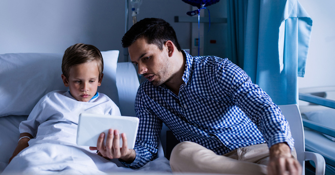 Father and son using digital tablet at hospital