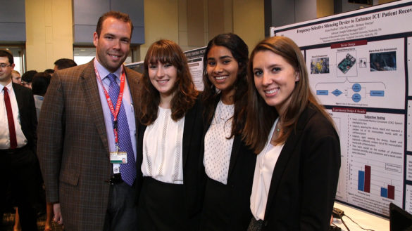 team in front of research poster at design day