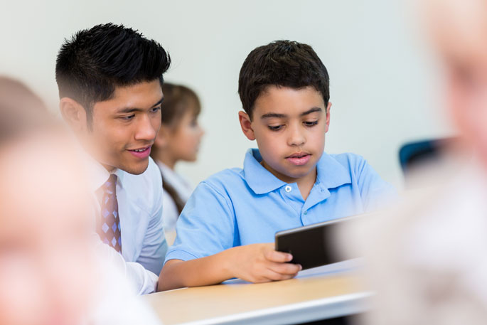 Student using iPad with teacher