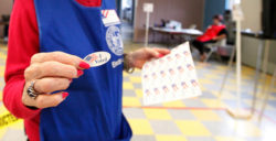 Volunteer handing out I Voted stickers after filling out a election ballot at a district voting station