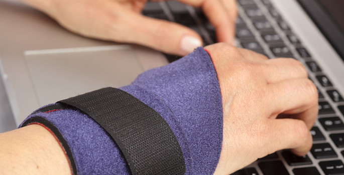 close-up of hand wearing wrist brace while typing