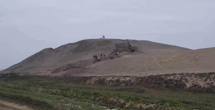 distance view of temple mound with tiny people atop it for scale