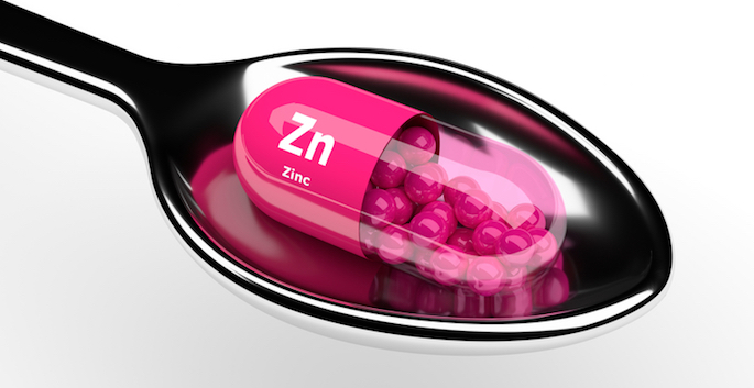 zinc pill on spoon over white background