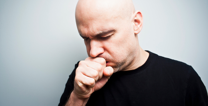 Man holds his hand over his mouth while coughing into it