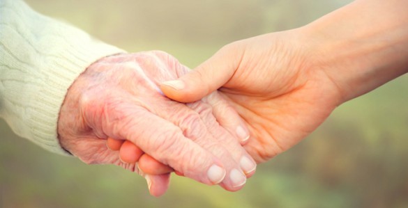 Elderly woman holding hands with young caretaker