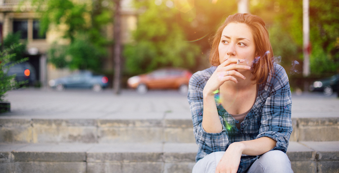 sad woman sitting outside smoking