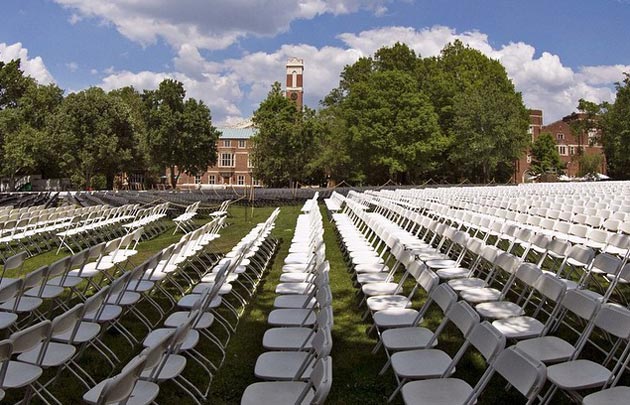 Chairs set up on Alumni Lawn ahead of Commencement exercises, with a view of the Kirkland clock tower in the distance.