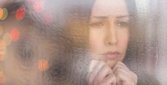 sad woman looking through a window