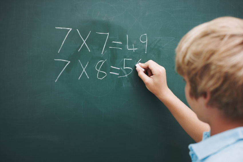 child writing math on blackboard