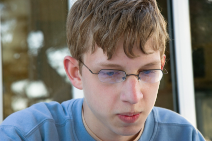 Teenage boy with glasses thinking