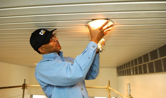 Anthony Hayes of VUMC Plant Services' electrical shop installs LED energy efficient light bulbs at Eskind Biomedical Library. (Anne Rayner/Vanderbilt)