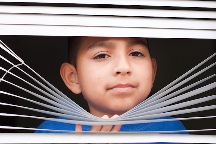 Boy looking through blinds