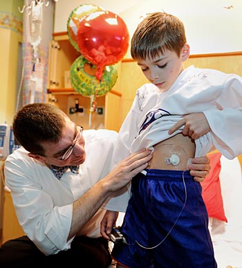 Drew Bremer, M.D., Ph.D., examines the new insulin pump and monitor recently placed on 10-year-old Jackson Sevelius' abdomen for a new type 1 diabetes study at Vanderbilt. (photo by Joe Howell)