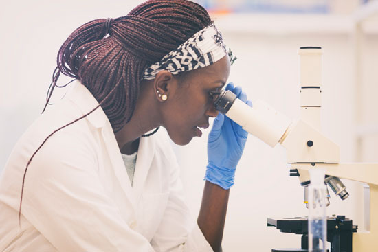 Photo of African American woman looking through a microscope