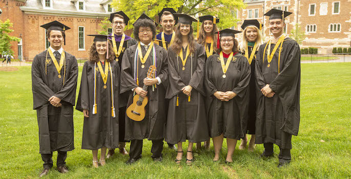 students in robes standing outside