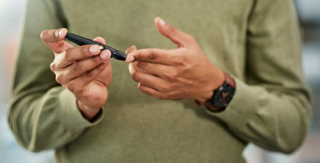 Closeup shot of an African American man testing his blood sugar level
